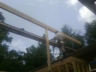 Carpenter setting a ridge beam over a new addition frame — Ice Dam Removal by Roofing Brothers in Polkton