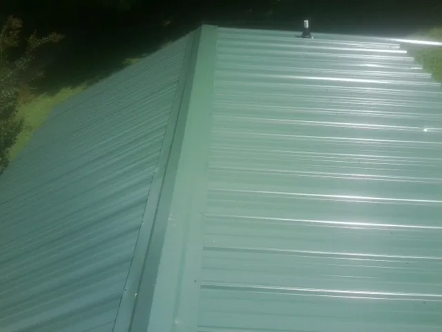 New green metal panels meeting at the ridge of a roof — Flat Roof Repair work by our crew in Polkton