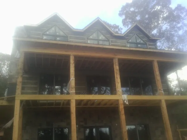 Dormers and porch framing on a large log home under construction — Roof Coating work by our crew in Polkton