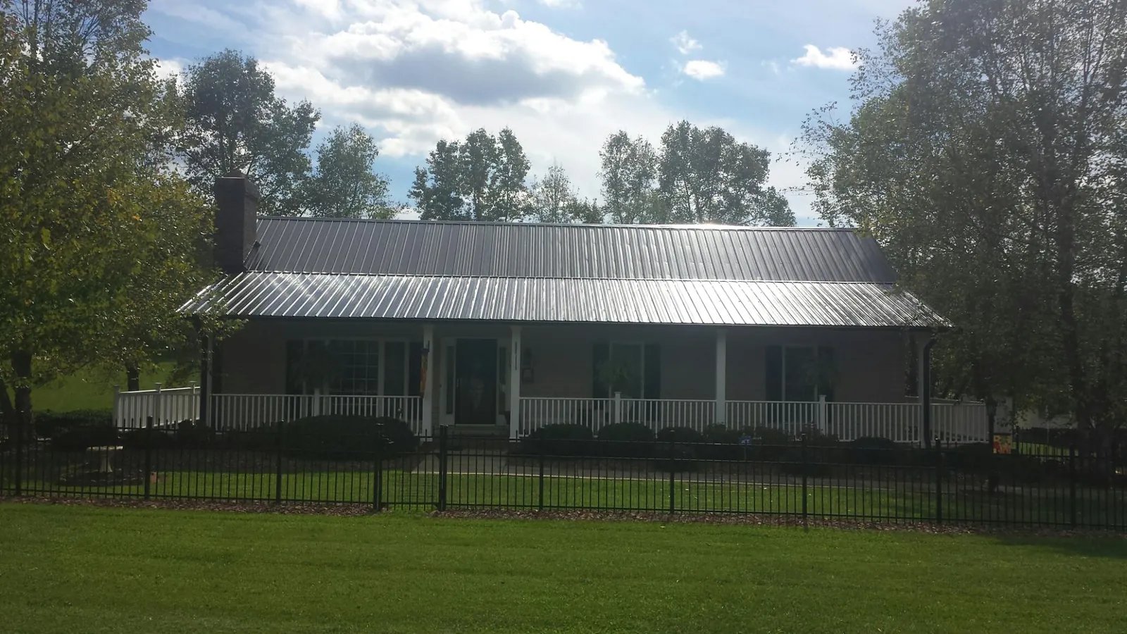 Gray metal roof on a brick ranch with a full width front porch — Gutter Guard Installation work by our crew in Polkton