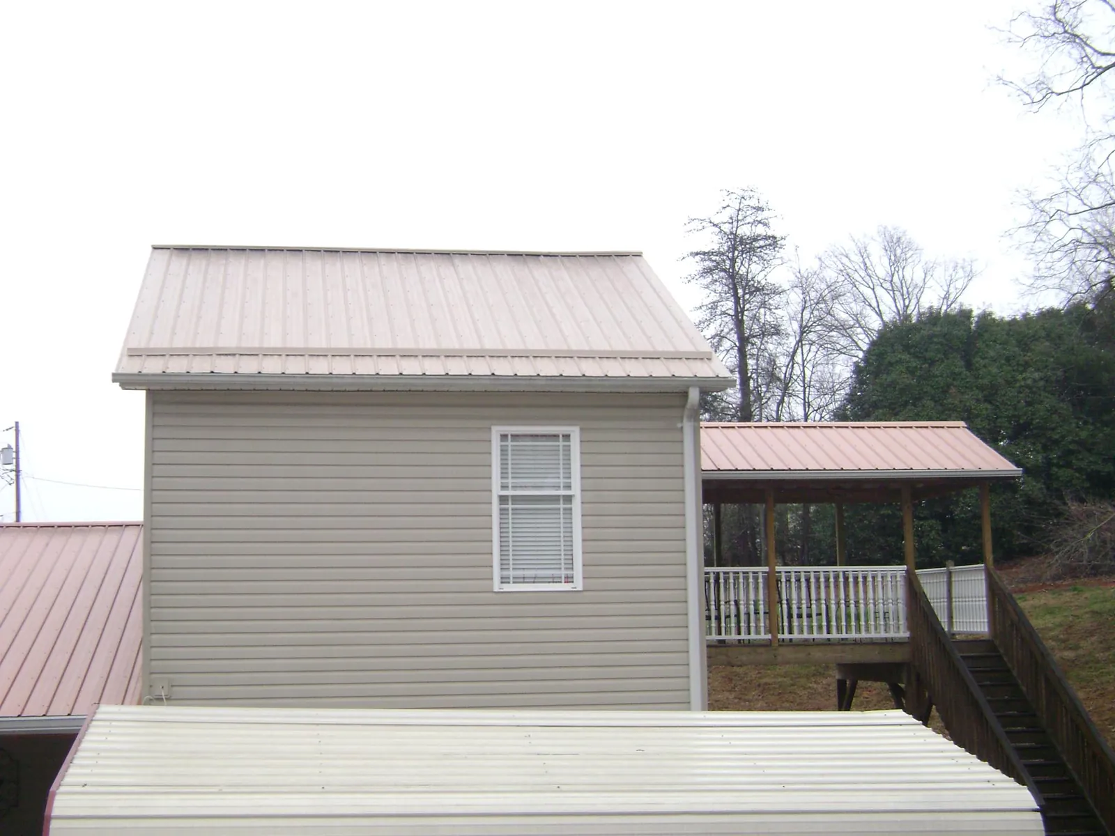 Tan metal roofs on a two story addition and attached porch, from a Roof Replacement job in Polkton