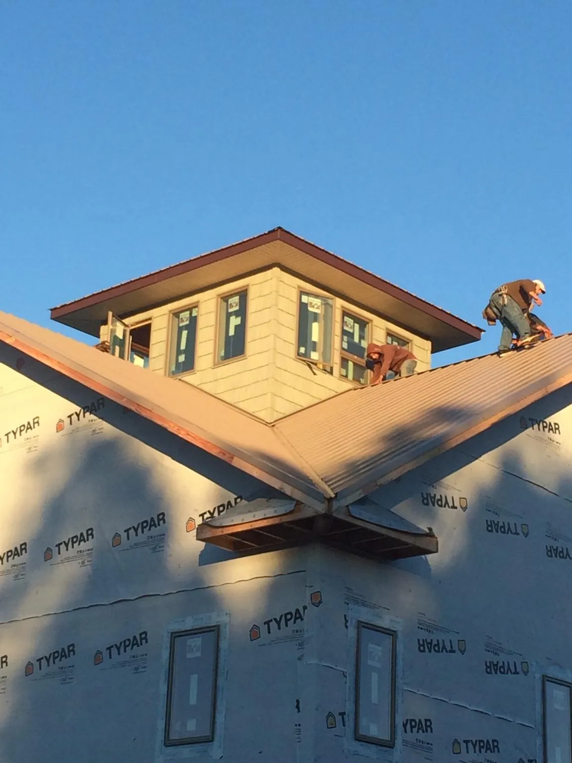 Roofers working around a rooftop cupola on a new metal roof at sunset — Roof Waterproofing in Polkton by Roofing Brothers
